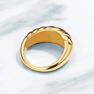 Macro shot of wide gold braided twist ring on elegant white marble surface texture