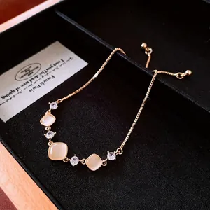 Adjustable gold chain bracelet featuring square cat-eye stones and cubic zirconia accents