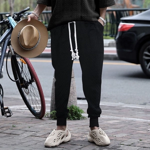 Men's black casual drawstring pants with jacquard texture shown in an outdoor street setting