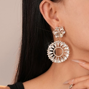 Detailed close-up of a model wearing gold floral hoop earrings with sparkling rhinestones