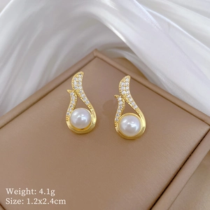 Macro detail of gold earrings with white pearls and diamonds on a brown jewelry box