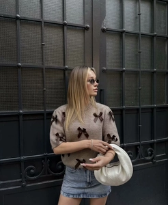 Détail d'un pull en tricot marron à manches courtes avec des nœuds 3D décoratifs