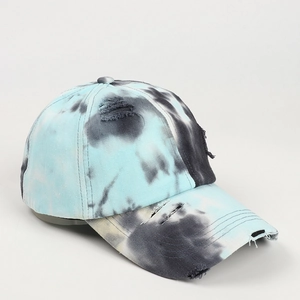 Detail of distressed tie-dye baseball cap with blue ink textures and frayed hole effects