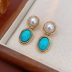 Close-up of vintage gold earrings with white pearl and blue turquoise on a wooden tray