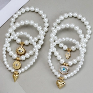Detailed view of four-piece pearl bead bracelets with golden Evil Eye and Hand of Fatima charms