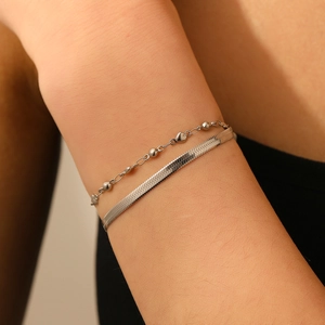 Gros plan de bracelets double couche en acier argenté avec breloque cœur et chaîne serpent plate