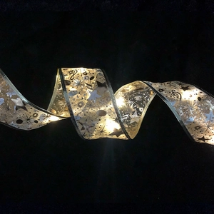 Golden and silver LED Christmas ribbon with warm glowing stars and musical notes patterns
