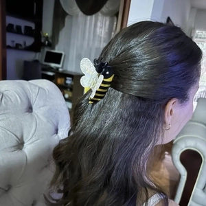 Detailed view of an acrylic bee hair claw clip styled on a woman's long wavy dark hair