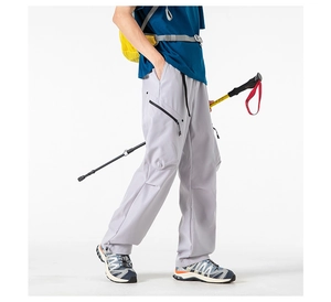 Detail of grey outdoor cargo pants with utility pockets and black drawstring waist