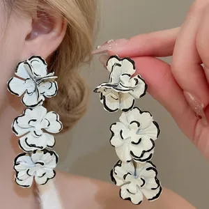 Elegant white enamel flower tassel earrings with black outlines and three-tiered petal design