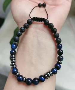 Detail of beaded Morse code bracelet with natural lava stone and tiger eye on wrist