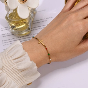 Detail of vintage stainless steel cross bracelet with colorful beads on female wrist