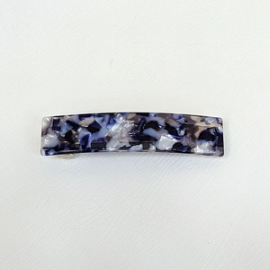 Dettaglio del fermaglio per capelli in acetato con motivo marmorizzato blu e bianco