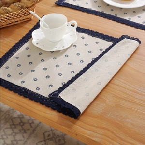 Macro detail of Nordic blue floral linen placemat with crochet lace edge on a wooden table