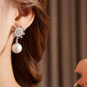 Gros plan d'une boucle d'oreille flocon de neige argentée avec zircon et perle sur un mannequin