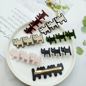 Detailed close-up of cute cat-shaped acetate hair clips in assorted colors on a white plate