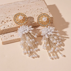 Détail de boucles d'oreilles à franges luxueuses avec perles et strass sur marbre