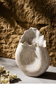 Macro detail of white ceramic vase with textured swirls and wavy rim on stone background