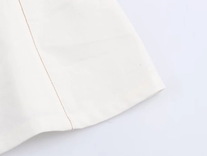 Détail du tissu sergé blanc avec surpiqûres orange contrastées sur l'ourlet