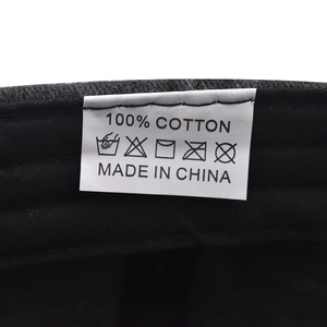 Close-up of internal wash care label on black cotton baseball cap showing 100% cotton material