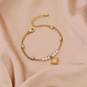 Elegant gold double-layer star pearl bracelet with clover pendant on silk background