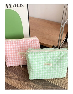 Vue détaillée de trousses à maquillage matelassées à carreaux roses et verts sur bois