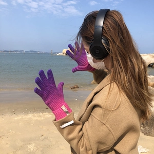 Close-up of rainbow gradient knit gloves with touch screen function on a sunny beach