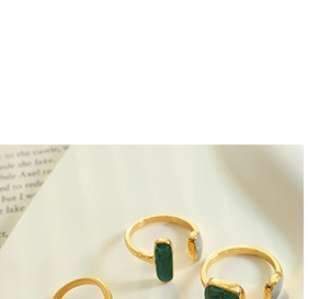 Close-up of golden open ring featuring rectangular green enamel inlay and sleek metal band