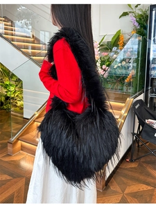 Detail of a large black faux fur heart-shaped bag with tassels shown on model