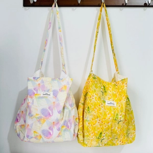 Detail of floral and butterfly canvas tote bags hanging on a white wall