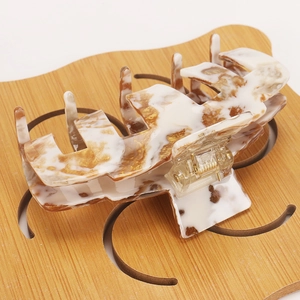 Detail of large acetate hair claw with white marble pattern and gold accents