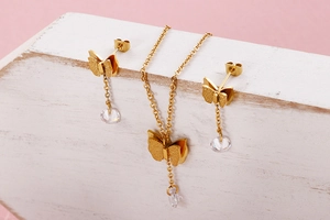 Details des vergoldeten Schmetterling-Schmucksets mit Zirkonia-Anhängern auf Holzblock