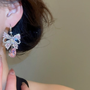 Close-up of sparkling pink crystal bow earrings featuring a drop-shaped teardrop pendant