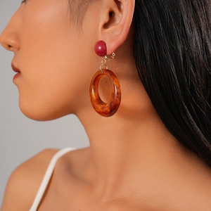 Détail macro de boucles d'oreilles en résine rétro au motif écaille avec accents dorés