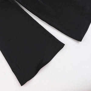 Détail de couture fine et texture tissée sur l'ourlet d'une robe en satin noir