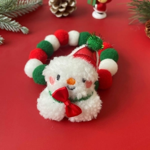 Detailed close-up of a Christmas pet collar with snowman charm and plush pom-poms