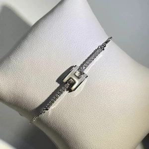 Detailed macro shot of silver T-shaped bracelet with mother-of-pearl inlay and zircons