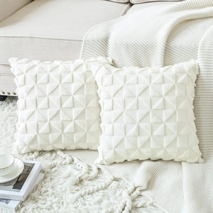 Set of two white plush throw pillow covers with geometric triangle texture on sofa