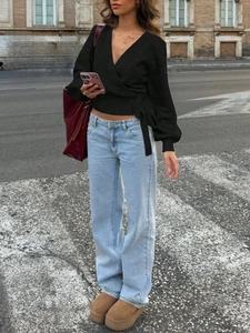 Detail of cross V-neck wrap knitted top with side bow tie and high waist wide leg jeans