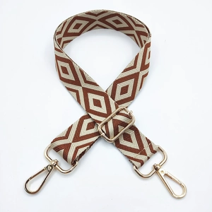 Detail of adjustable embroidered bag strap with brown geometric pattern and gold hardware