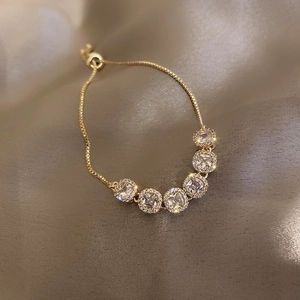 Detail of adjustable gold bracelet with square crystals on champagne silk background