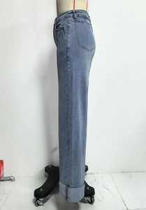 Detailweergave van hoge blauwe jeans met vintage omslag en wijd uitlopende pijpen