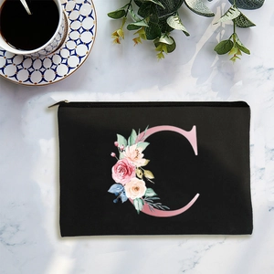Minimalist black canvas cosmetic bag with floral letter C on white marble surface