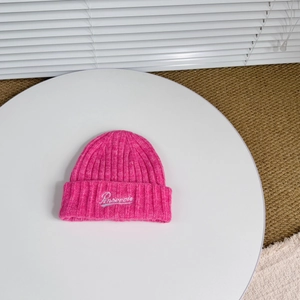 Detail of rose pink ribbed knit wool hat featuring white cursive letter embroidery