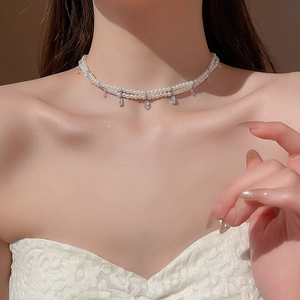 Detailed close-up of double-layer pearl necklace with a teardrop crystal pendant on model