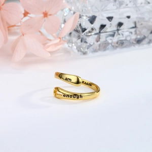 Dettaglio anello in argento s925 dorato con incisioni Faith e Enough su sfondo bianco