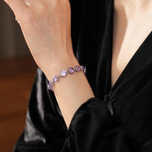 Detailed view of wrist wearing a purple round zircon tennis bracelet in silver setting