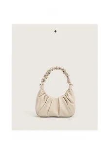 Detail of cream pleated cloud bag showing soft wrinkled texture and handle design