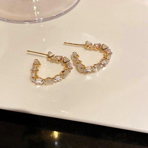 Detail of gold C-shape hoop earrings with white zircon and cat's eye stones inlay