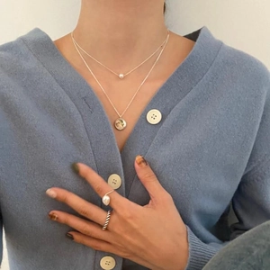 Minimalist 925 sterling silver layered necklace with pearls and rings on a model